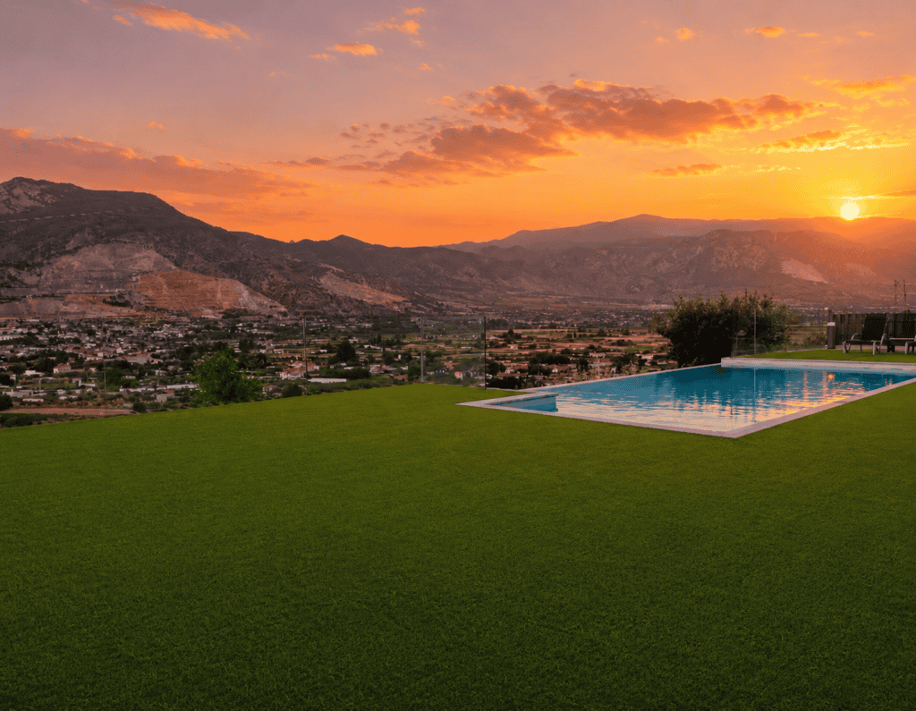 Instalación de césped artificial junto a piscina infinita con vistas a la montaña